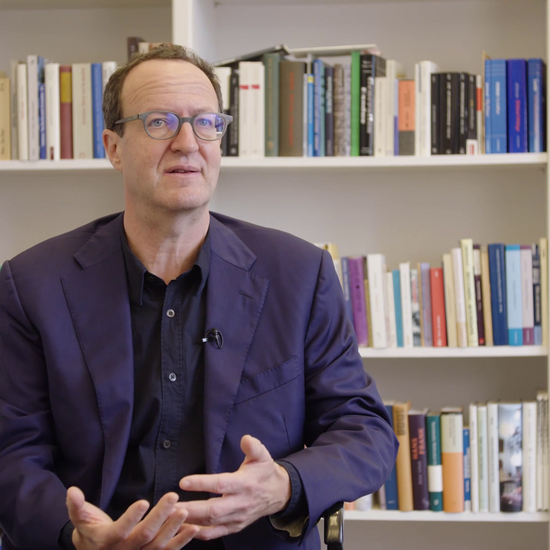 Raphael Gross sitzt vor einem Bücherregal spricht zur Kamera.