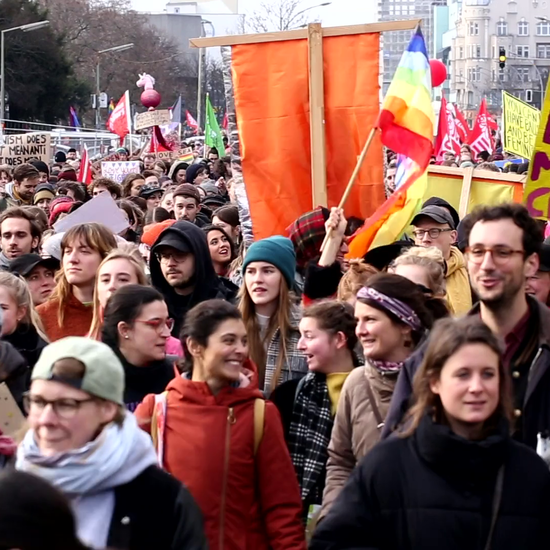 Menschen versammeln sich auf der Straße und halten Flaggen in der Hand.