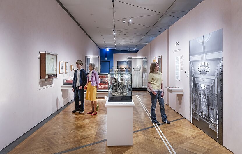 In der Ausstellung „Objekte. Geschichte. Geschichten. Blick in die Sammlung” Menschen stehen in einer Ausstellung