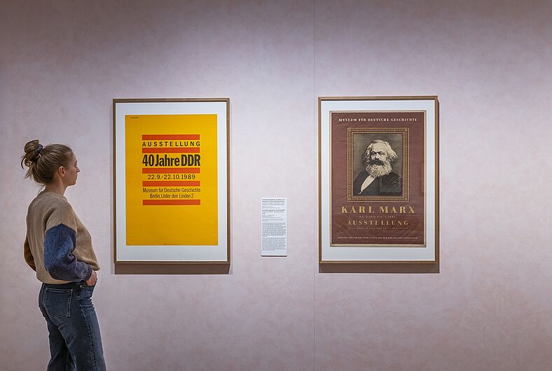 In der Ausstellung „Objekte. Geschichte. Geschichten. Blick in die Sammlung” Menschen stehen in einer Ausstellung