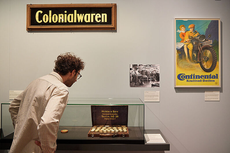 In der Ausstellung „Umstrittene Verwandtschaft. Koloniale und nationalsozialistische Gewalt” Menschen stehen in einer Ausstellung