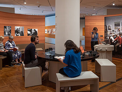 Personen beschäftigen sich mit verschiedenen Objekten in der Ausstellung.