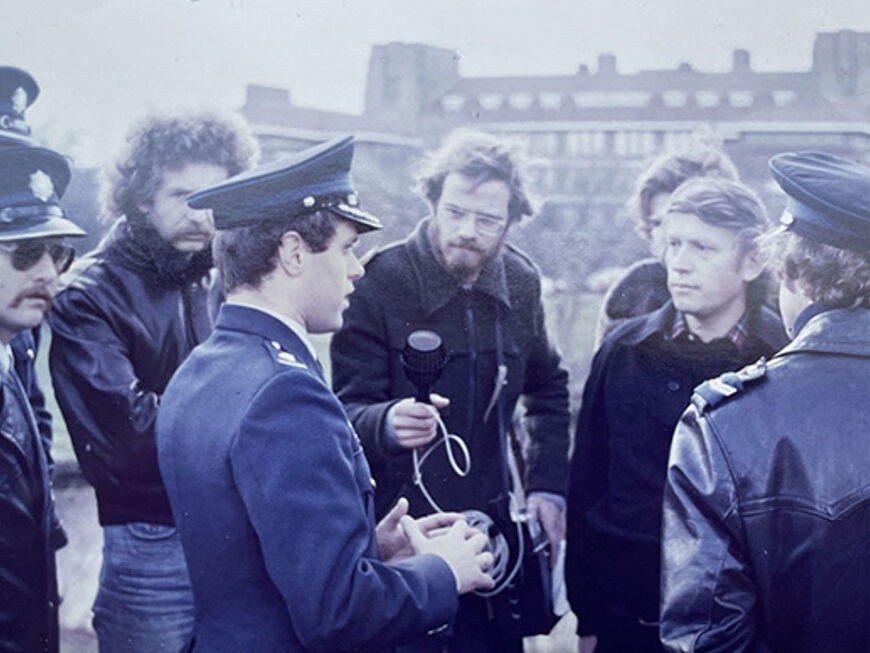 Ein Mann wird auf der Straße interviewt und Menschen stehen um ihn herum.