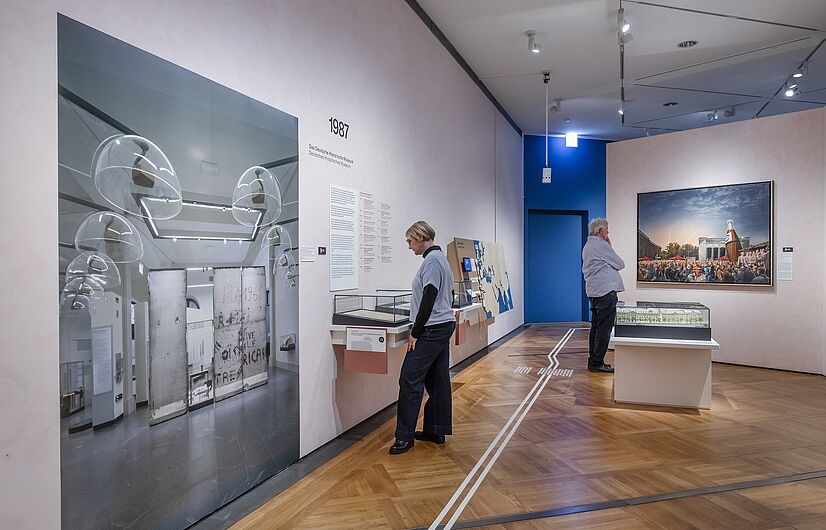 In der Ausstellung „Objekte. Geschichte. Geschichten. Blick in die Sammlung” Menschen stehen in einer Ausstellung